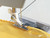 Husqvarna Viking shell rolled hem foot creating decorative edge on yellow fabric - presser foot