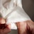 Person inspecting hand-sewn hemline on white fabric.