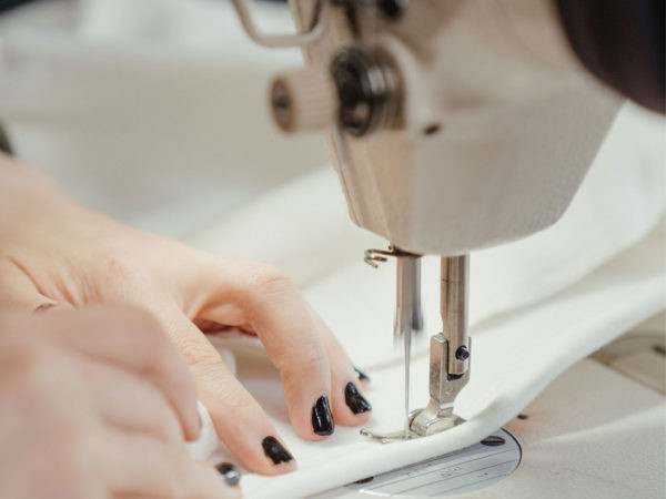 A woman learning sewing essentials by putting a piece of fabric with a sewing machine.