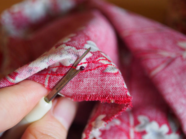 Close up of a seam ripper being used on stitching.