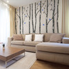 Dark brown birch forest wall decals with blue birds creating a large nature-inspired living room feature wall