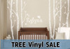 White woodland tree wall decals with birds and personalized name Roselynn above a dark wood crib
