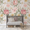 Olena vintage pink floral wallpaper in a nursery with a black metal crib and wooden rocking horse