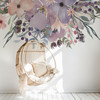 Wild Spring Garden watercolor floral wall decal border with pink lavender and blue flowers above a hanging chair in a soft neutral nursery