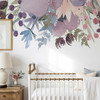 Watercolor flower wall decal border with soft pink purple and blue wildflowers above a white metal crib in a baby nursery