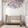 Pastel watercolor floral wall decal border above a natural wood crib in a bright nursery with white walls and large windows
