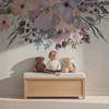 Pastel watercolor floral wall decal border above a changing dresser with stuffed animals in a soft neutral baby nursery