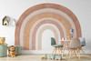 Large terracotta watercolor rainbow wall decal displayed in a children’s playroom with a table, chairs and toys