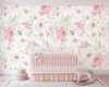 Pink watercolor floral wallpaper behind a blush nursery crib with classic décor