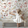 Little girl admiring Beatrice Wildflower Wallpaper featuring watercolor botanical flowers in an English Cottage nursery