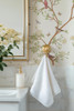 Close-up of Selina Chinoiserie wallpaper with delicate botanical branches, flowers, and soft green leaves beside a classic bathroom towel hook 26 repeat