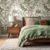 Oversized green and brown foliage wallpaper in a masculine bedroom with layered green bedding shown in the 52-inch scale