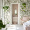 Neutral fern and meadow grass wallpaper framing a bright bedroom doorway and adjoining dressing area