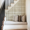 Neutral beige plaid wallpaper in 26 inch repeat styled in an under stairs reading nook with bench cushion, pillows, and black stair railing