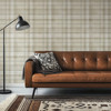 Neutral beige plaid wallpaper in 26 inch repeat styled behind brown leather sofa with black floor lamp, patterned rug, and masculine living room decor