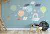 Colorful watercolor balloon, rainbow and cloud wall decals displayed on a blue playroom wall above children’s furniture