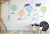 Watercolor travel balloon wall decals with clouds, birds and rainbow displayed above a children’s table on a blue wall