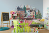 Colorful fairytale town wall decal displayed behind a children’s play table in a bright playroom