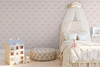Pink ribbon wallpaper in a baby girl nursery with an ivory canopy bed and soft neutral furnishings