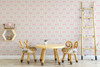 Small-scale pink bow wallpaper in a children’s playroom with wood table and animal-shaped chairs