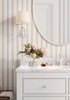 Blue striped wallpaper with warm gold accents styled in a nursery with a soft modern look