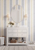 Blue striped wallpaper with warm gold accents styled in a nursery with a soft modern look