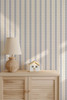 Blue striped wallpaper with warm gold accents styled in a nursery with a soft modern look