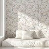 Magnolia Chinoiserie Wallpaper styled in a bright bedroom with white bedding, window light, blush magnolia flowers, and soft botanical walls