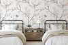 Magnolia Chinoiserie Wallpaper styled in a twin bedroom with white beds, wood nightstand, blush floral branches, and soft botanical wallpaper