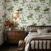 Weathered Green Cowboy Wallpaper styled in a moody bedroom with wood nightstand, wall sconce, layered bedding, boots, and vintage rodeo wall pattern