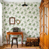 Weathered Green Cowboy Wallpaper styled in an entryway with wood table, vintage luggage, warm wood door, framed art, and green rodeo wall pattern