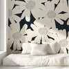 Oversized cream flower wallpaper on a black accent wall behind a white daybed