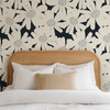 White Blooms floral wallpaper shown at the 52-inch scale behind a curved wood headboard