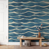 Coastal blue wave embossed wallpaper in an entryway with natural wood bench and warm ivory trim