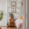 Chinoiserie wallpaper with soft botanical branches and birds styled in a neutral nursery