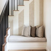 Neutral linen stripe wallpaper in a staircase reading nook with a built-in bench