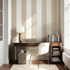 Beige vertical stripe wallpaper in a home office with a wood desk and white chair