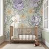 Sarah sage green floral wallpaper with oversized lavender, cream and yellow botanical flowers behind a natural wood crib