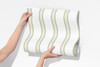 Wallpaper roll sample showing Charlotte Stripe sage green and pink striped wallpaper design