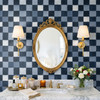 Blue checkered bathroom wallpaper with oval gold mirror, brass sconces, marble vanity, and navy plaid pattern