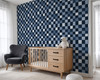 Blue checkered nursery wallpaper with crib, wood dresser, black chair, and navy plaid accent wall