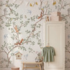 Woodland chinoiserie animals wallpaper in a soft nursery with crib and tree branch pattern