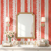 Pink lace stripe wallpaper behind a bathroom vanity with gold sconces