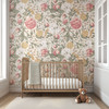 Romantic floral nursery wallpaper behind a wooden crib with oversized vintage roses and botanical leaves
