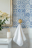 Blue Moroccan geometric wallpaper close-up in bathroom with brass towel hook, 13-inch repeat