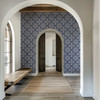 Blue French country tile wallpaper in 26-inch repeat in an entryway with white arches, wood bench, and neutral rug
