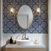 Blue fleur-de-lis tile wallpaper in 26-inch repeat in a French country bathroom with oval mirror and white vanity. 26-Inch Repeat