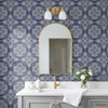 Navy blue geometric tile wallpaper in 26-inch repeat in a modern French bathroom with arched mirror and brass sconces