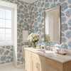 Linnea blue watercolor floral wallpaper in 26 inch repeat styled in a bright bathroom with wood vanity, silver mirror, white flowers, and marble countertop