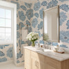 Linnea blue watercolor floral wallpaper in 52 inch repeat styled in a bright bathroom with wood vanity, silver mirror, white flowers, and marble countertop